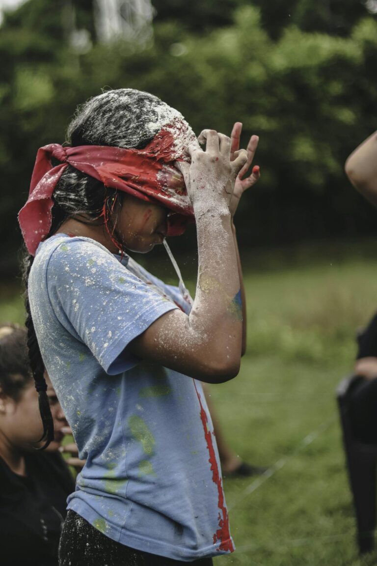 Girl playfully participating in a blindfold game at summer camp outdoors.